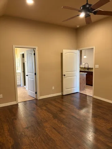 an empty room with wooden floor closet and windows