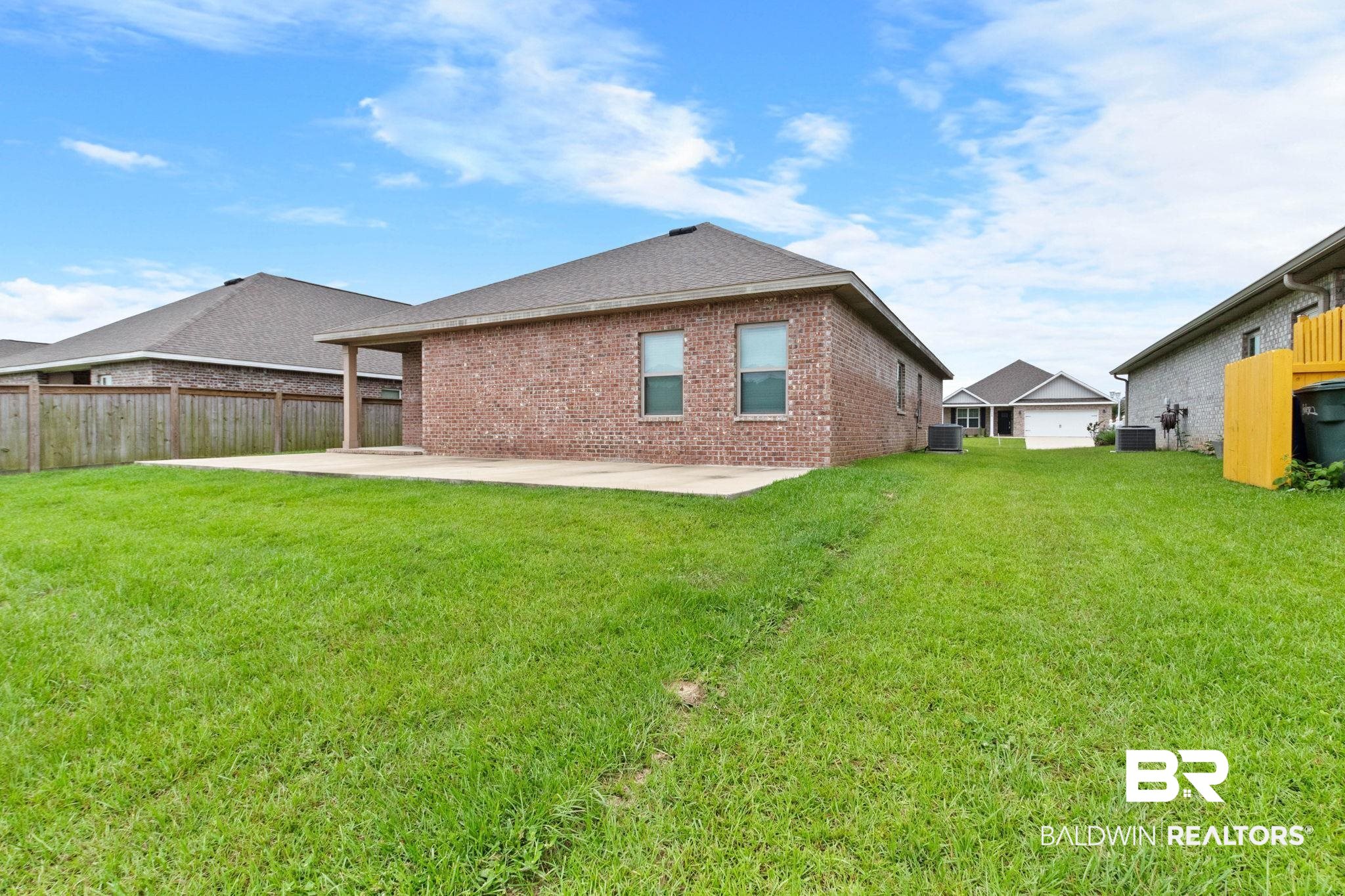 1710 Grouse Street Foley, AL 36535 - Photo 65 of 76 Expansive green lawn with a brick exterior home featuring a covered patio, dual pane windows, and a shingled roof