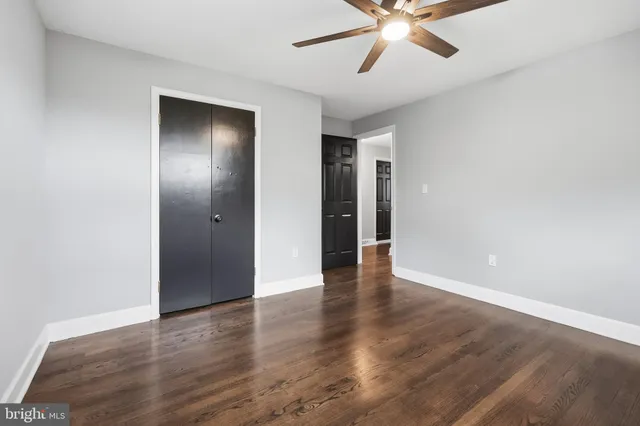 a view of an empty room with wooden floor and a ceiling fan