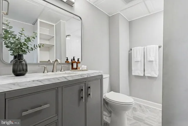 a bathroom with a granite countertop sink a toilet and mirror