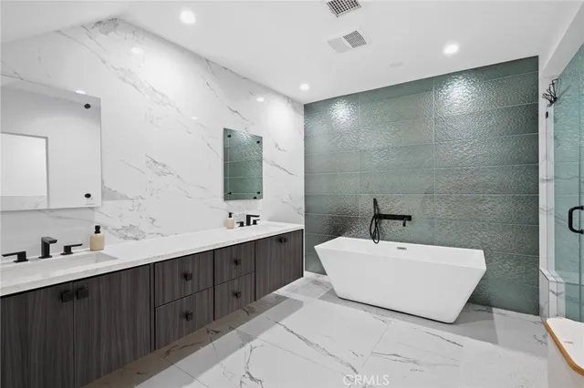 a bathroom with a double vanity sink mirror and bathtub