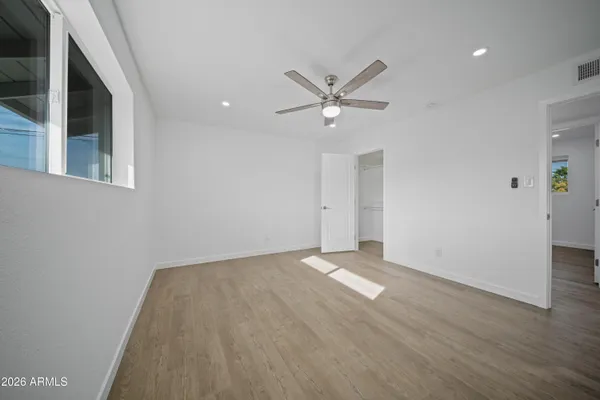 an empty room with a ceiling fan and wooden floor