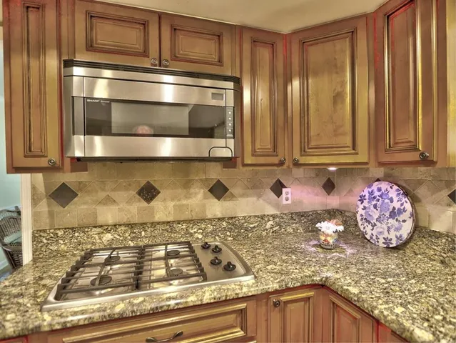 a dining hall with stainless steel appliances granite countertop a stove and cabinets