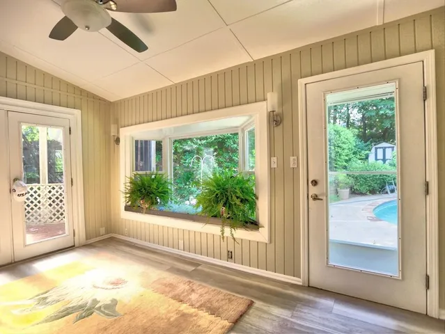an empty room with wooden floor chandelier and windows