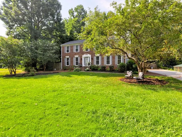 a view of a house with a big yard and large trees