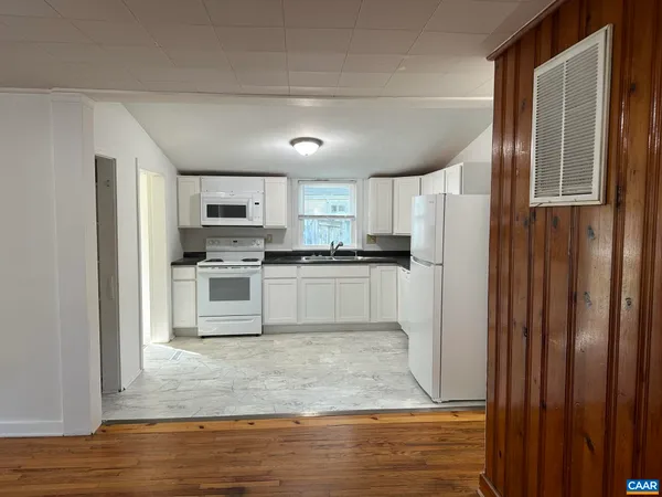 a kitchen with granite countertop a refrigerator and a stove top oven