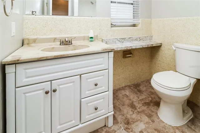 a bathroom with a granite countertop toilet sink and mirror