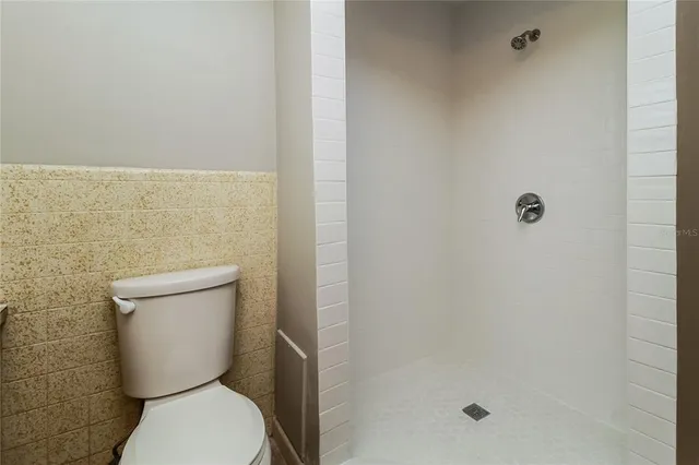 a white toilet sitting next to a shower