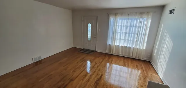 an empty room with wooden floor and windows