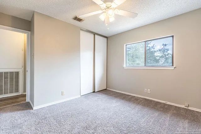 an empty room with windows and fan