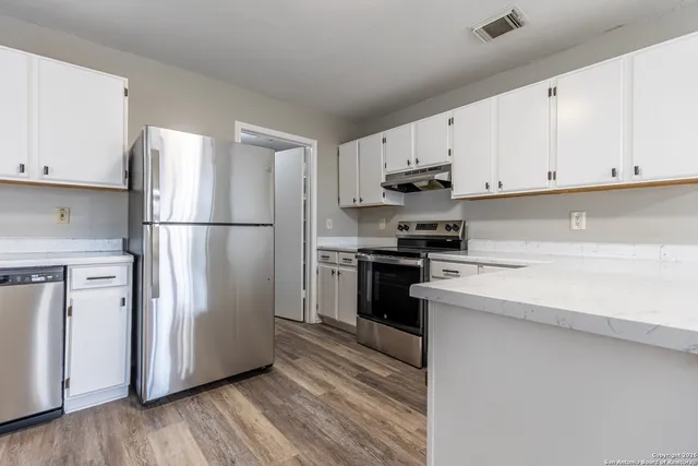 a kitchen with cabinets stainless steel appliances and wooden floor