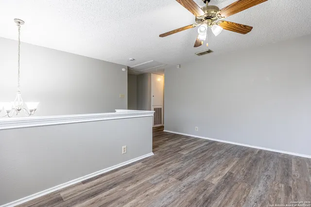 a view of an empty room with window and wooden floor