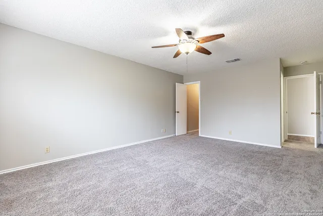 a view of an empty room with chandelier fan