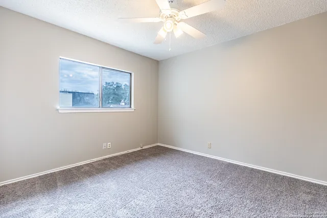 an empty room with a window and a fan