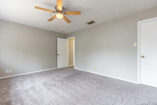 an empty room with a ceiling fan and a window