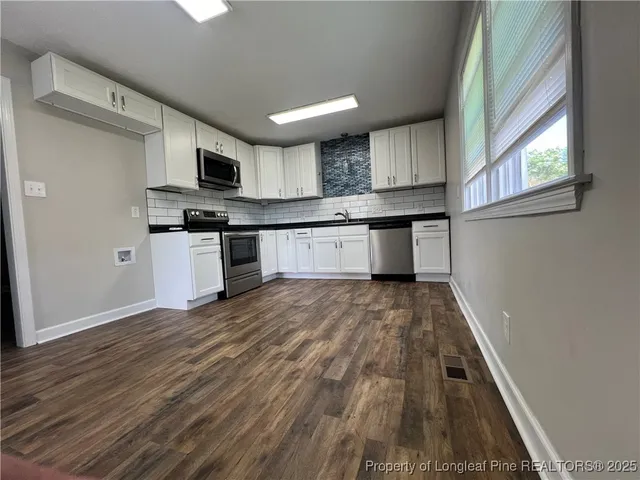 a large kitchen with stainless steel appliances granite countertop a stove and a wooden floors