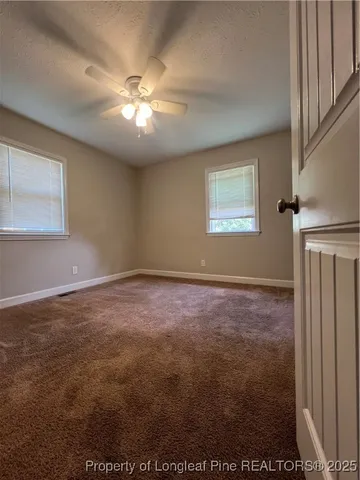 en empty room with windows and ceiling fan