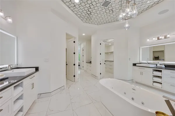 a large white bathroom with a granite countertop sink a toilet a mirror and bathtub