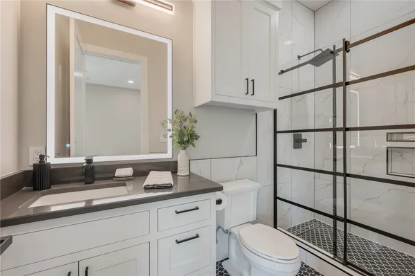 a bathroom with a granite countertop sink mirror vanity and toilet