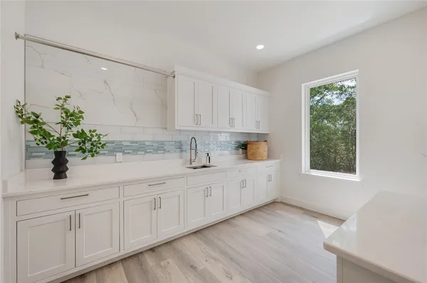 a kitchen with white cabinets and sink
