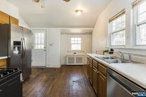 a kitchen with a sink wooden floor and stainless steel appliances