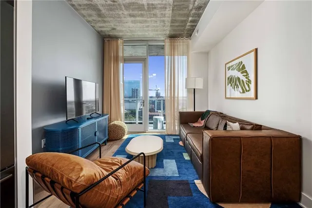 a living room with furniture a flat screen tv and a large window