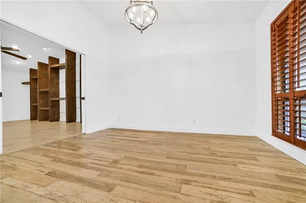 a view of empty room with wooden floor and fan