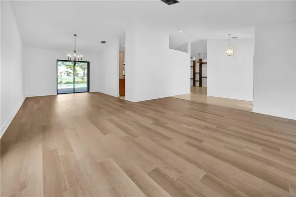 a view of an empty room with window and wooden floor
