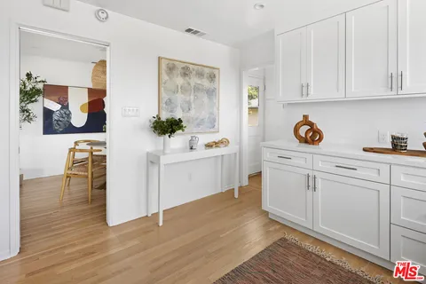 a kitchen with stainless steel appliances white cabinets and wooden floor
