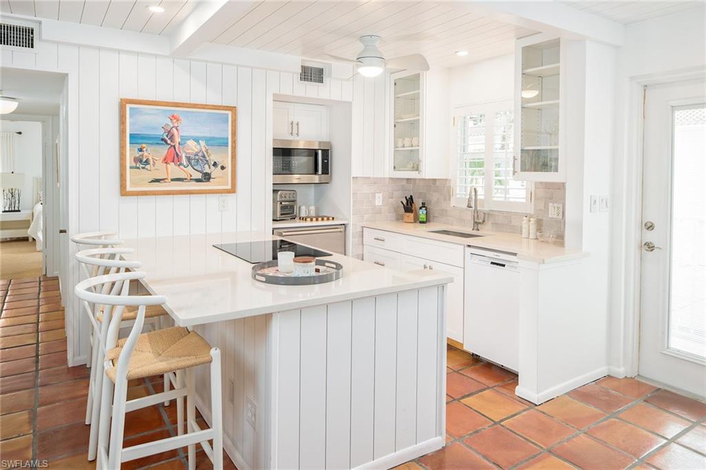 282 4th Street South, Unit 204 Naples, FL 34102 - Photo 2 of 16 a kitchen with stainless steel appliances a sink a stove a refrigerator a dining table and chairs