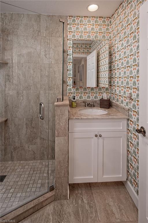 282 4th Street South, Unit 204 Naples, FL 34102 - Photo 8 of 16 a bathroom with a granite countertop sink a mirror and shower