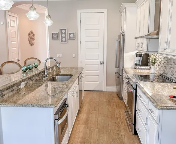 a kitchen with kitchen island granite countertop a sink stove and cabinets