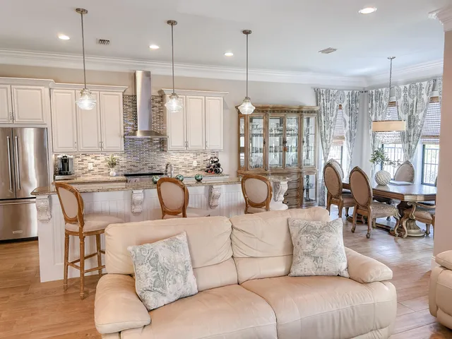 a living room with furniture kitchen area and a chandelier