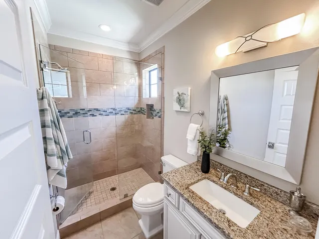 a bathroom with a granite countertop sink a toilet a mirror and shower
