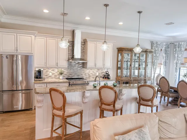 a kitchen with granite countertop a table chairs stove and refrigerator