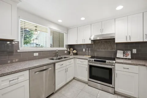 a kitchen with cabinets appliances a sink and a window