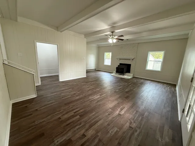 a view of a livingroom with wooden floor fireplace and window