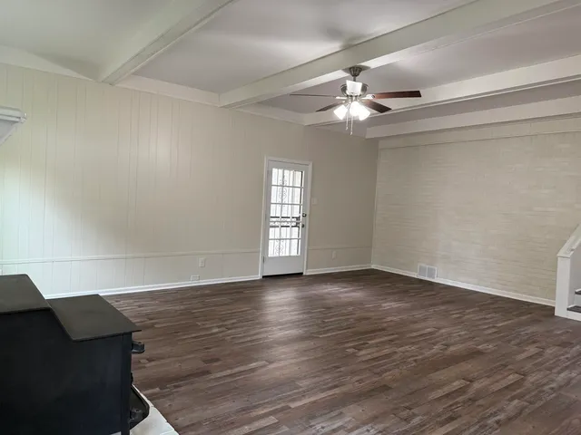 a view of an empty room with window and wooden floor