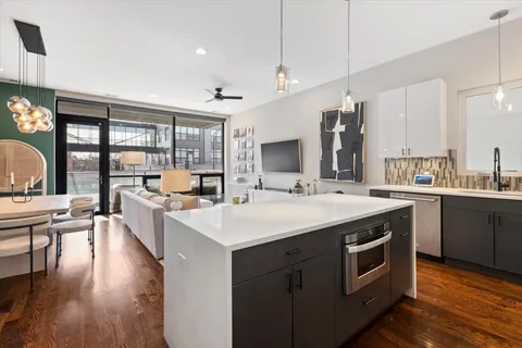 a open kitchen with stainless steel appliances a stove a sink dishwasher and a dining table with wooden floor