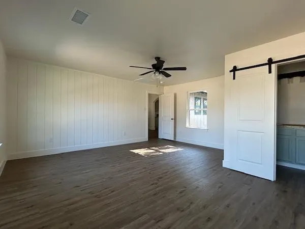 a view of an empty room with a window and wooden floor