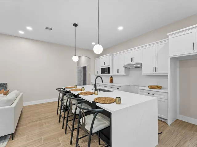 a kitchen with a dining table chairs and white cabinets