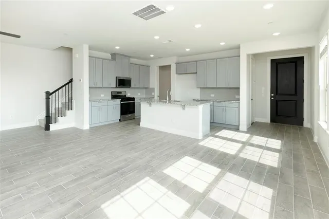 a kitchen with stainless steel appliances kitchen island granite countertop a refrigerator and a sink