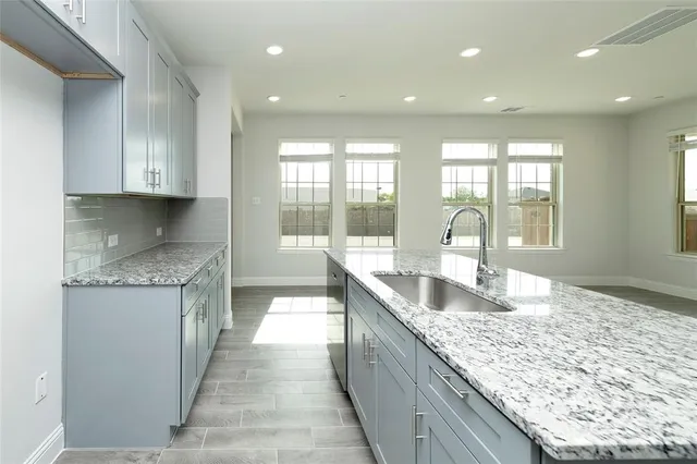 a large kitchen with granite countertop a sink and cabinets