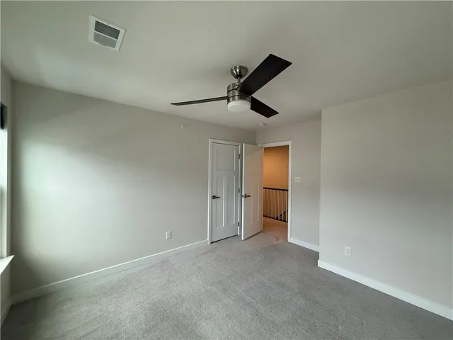 an empty room with a ceiling fan and window