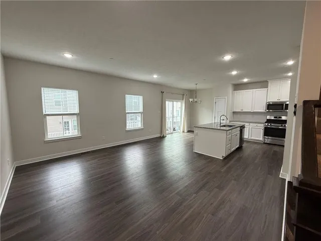 an open kitchen with white cabinets wooden floor and a refrigerator