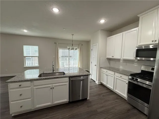 a kitchen with granite countertop a sink a stove cabinets and wooden floor