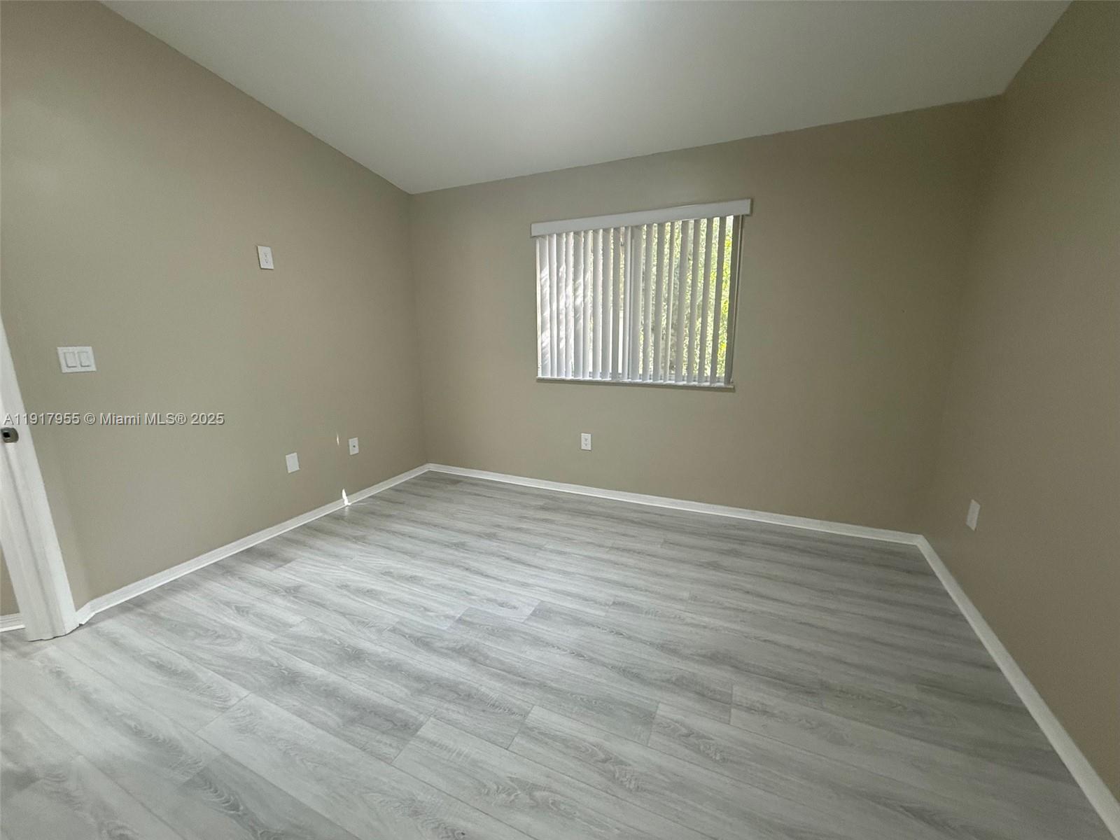 2911 Southeast 13th Road, Unit 20240 Homestead, FL 33035 - Photo 22 of 28 a view of an empty room with wooden floor and a window