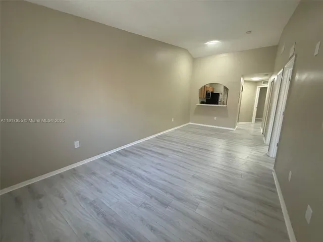 a view of a big room with wooden floor and a window