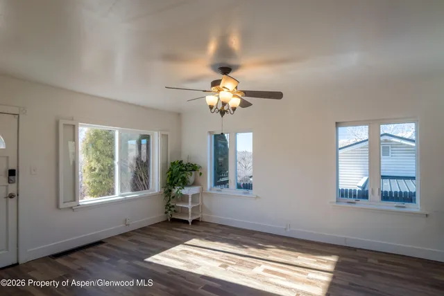 a view of an empty room with wooden floor and a window
