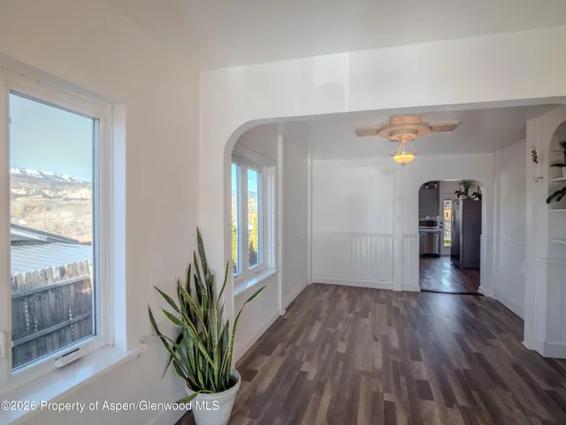 a view of a hallway to a livingroom with wooden floor and a staircase